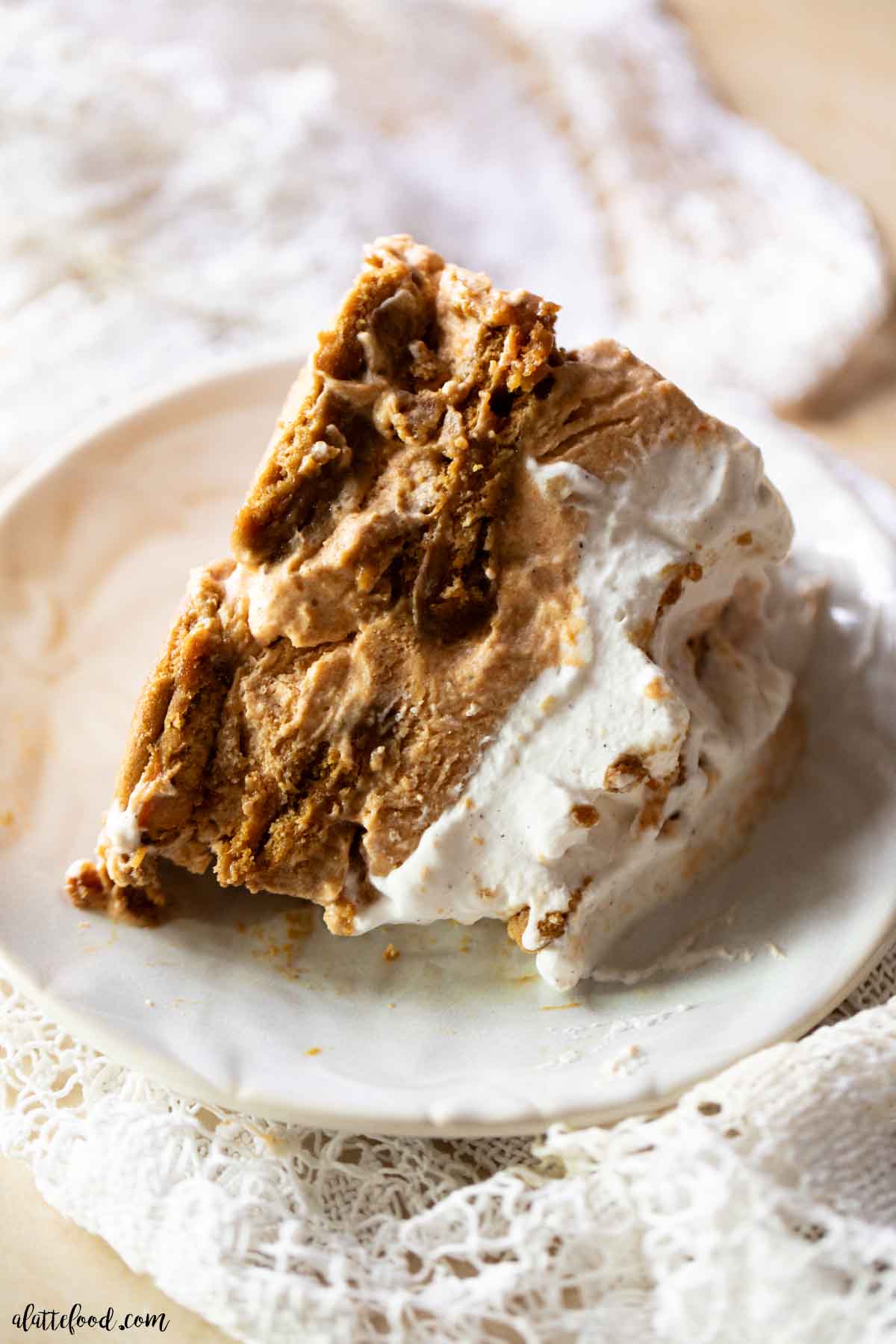 pumpkin gingersnap icebox cake slice on a cream plate sitting on a lace napkin.