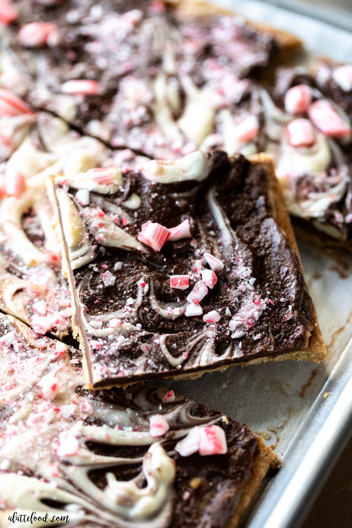 peppermint bark toffee cut into squares on a silver baking sheet.